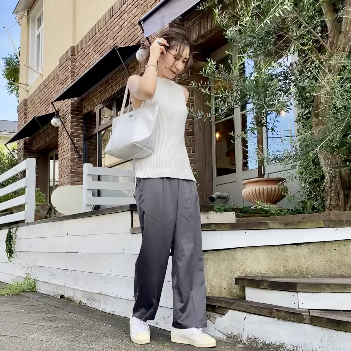 白ノースリーブニットにグレーパンツ、白スニーカーと白トートバッグ