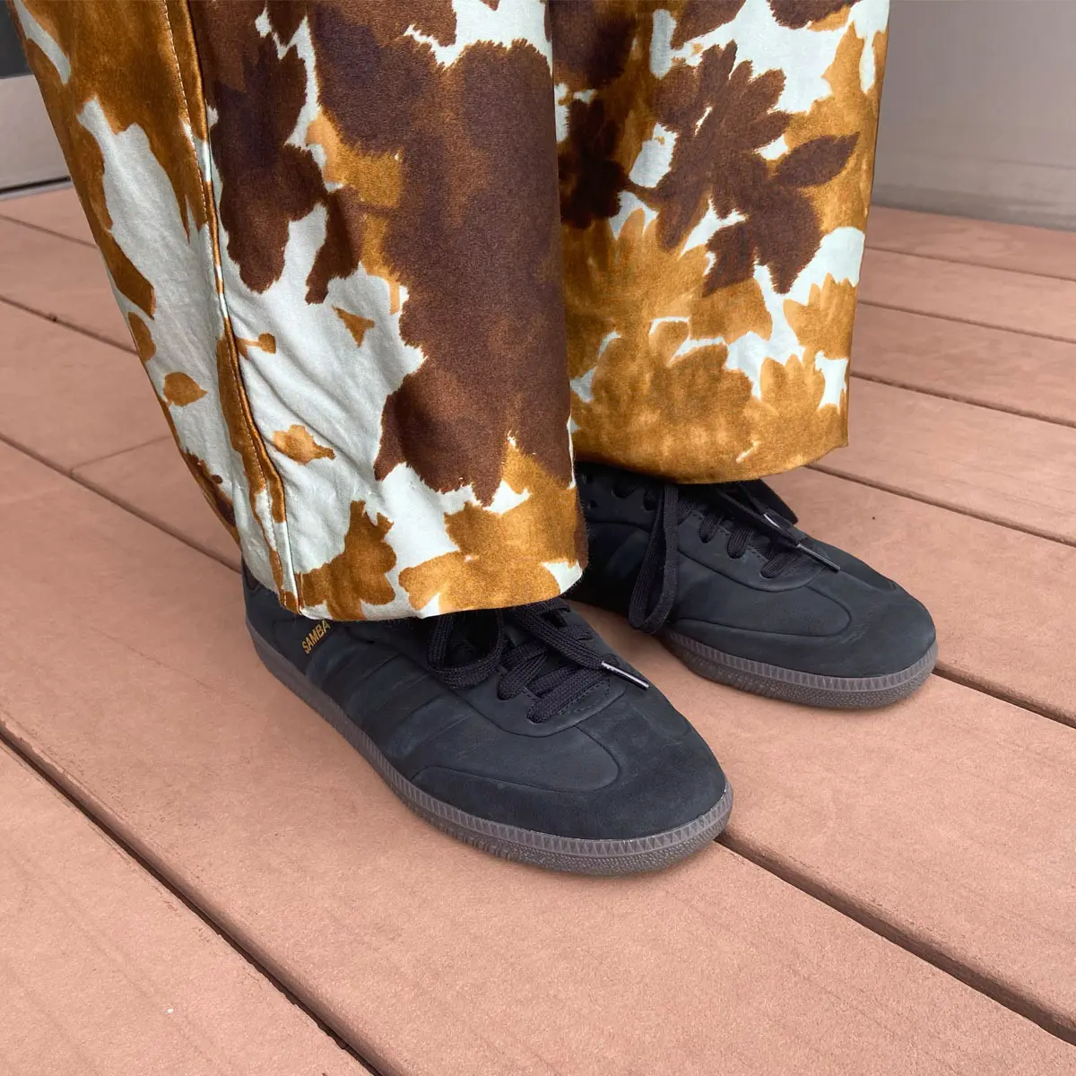 モード派の編集Tがプリントパンツに合わせたのは、控えめなスリーストライプがアクセントになったマットな黒のクラシックスニーカー。