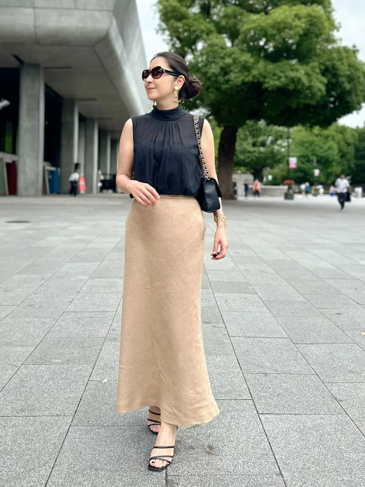 エクラプレミアムのキャメル「リネンフレアスカート」、黒のノースリーブブラウス、黒サンダル、黒のチェーンバッグ