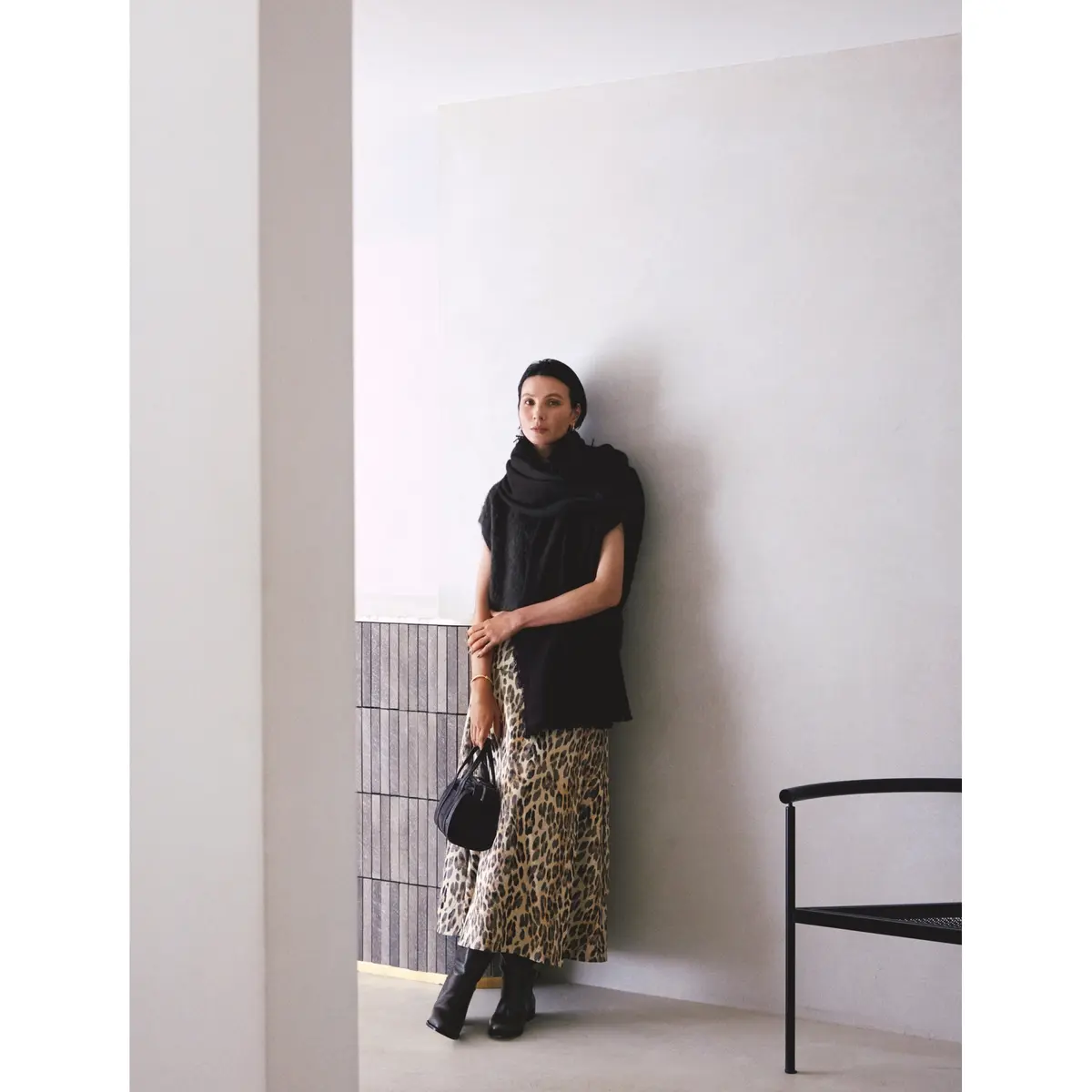 黒ショートスリーブニットの上から黒ニットマフラーをぐるぐる巻き、ボトムにレオパード柄ロングスカートを合わせたコーディネート　モデル・田沢美亜