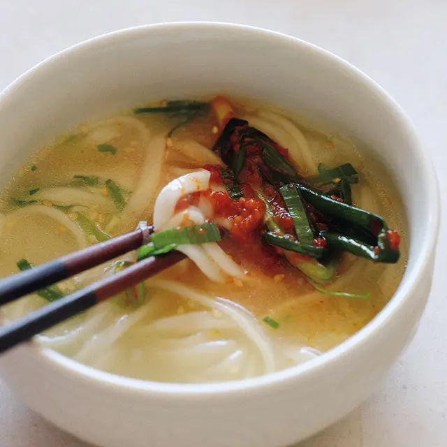 細うどんに細ねぎの即席キムチを加えるのもアリ。体にしみわたる黄金のスープは、最後まで飲み干したい