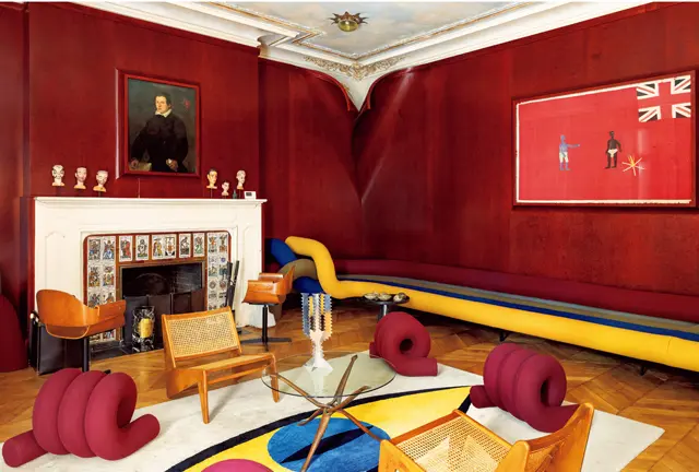カラフルな＂パイプ＂はラムダンがデザインしたソファ。右手の壁にはガーナ・ファンテ族の自警団の旗、左手にはクラシックな肖像画を飾り、コントラストを。ヴィンテージの椅子はピエール・ジャンヌレ、キャンドルスタンドはエットーレ・ソットサス。暖炉を飾るタロットカード風のタイルだけは、この家にもともとあった要素