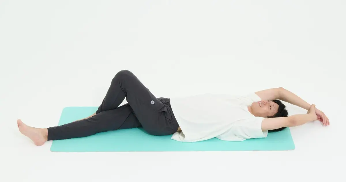 OurAge×Webエクラ　１）あお向けに寝て右脚を斜めに置き、左脚をクロスして右脚が動かないように固定します。