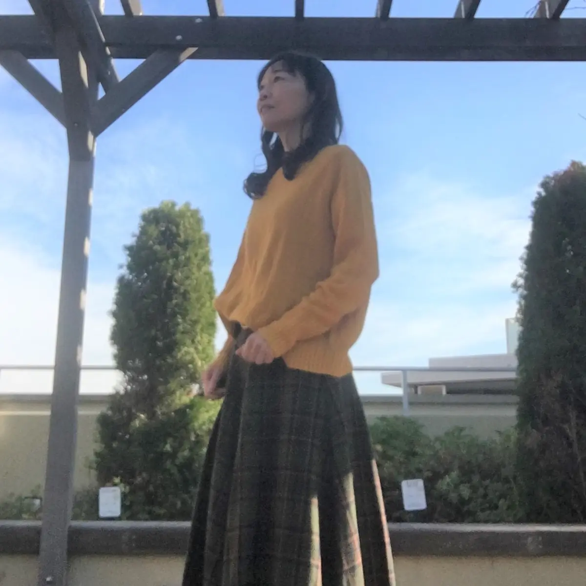 マスタードニットと濃いグリーンのチェックスカート（横から）