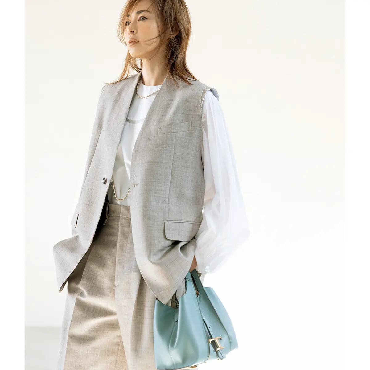 グレーのジレとパンツのセットアップに白ブラウスを合わせたコーデ　モデル・SHIHO