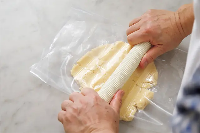 生地250gを取り出し、切り開い たポリ袋ではさみ、上からめん棒 でつぶし、転がし生地をのばす。