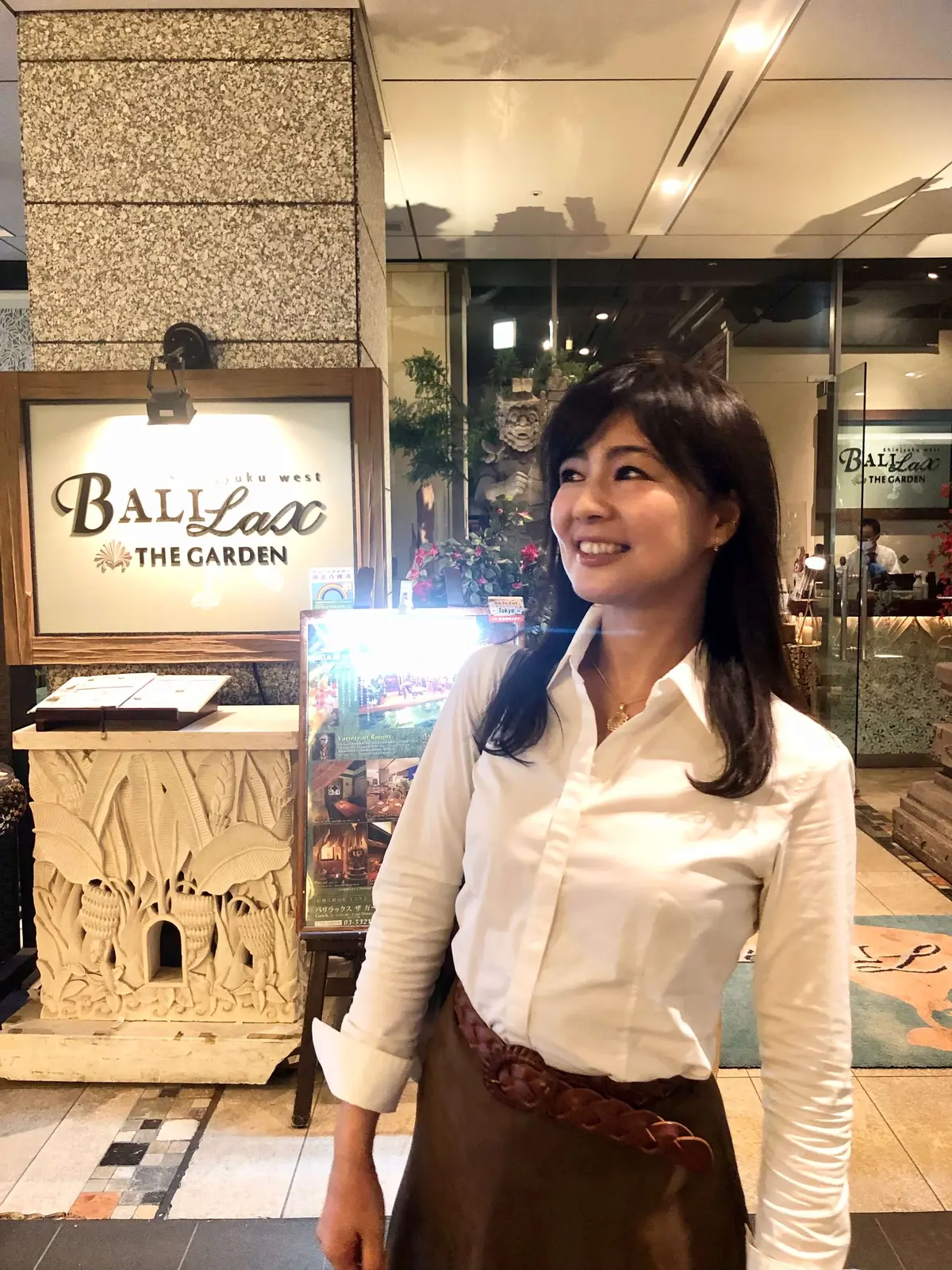 白いシャツにスエード調のスカート。ペンダントとベルトがポイント。