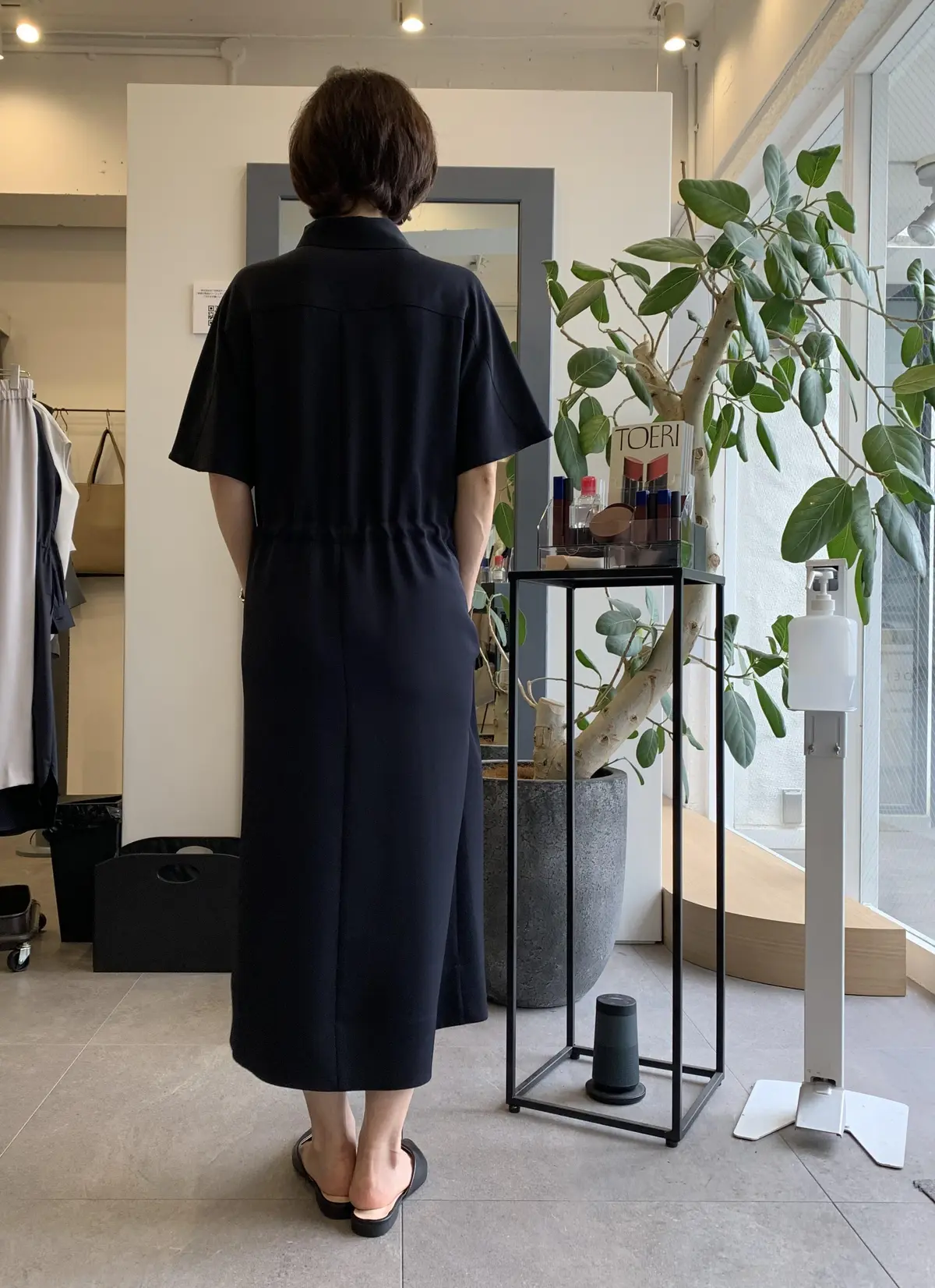 ネイビーのワンピースを試着する女性