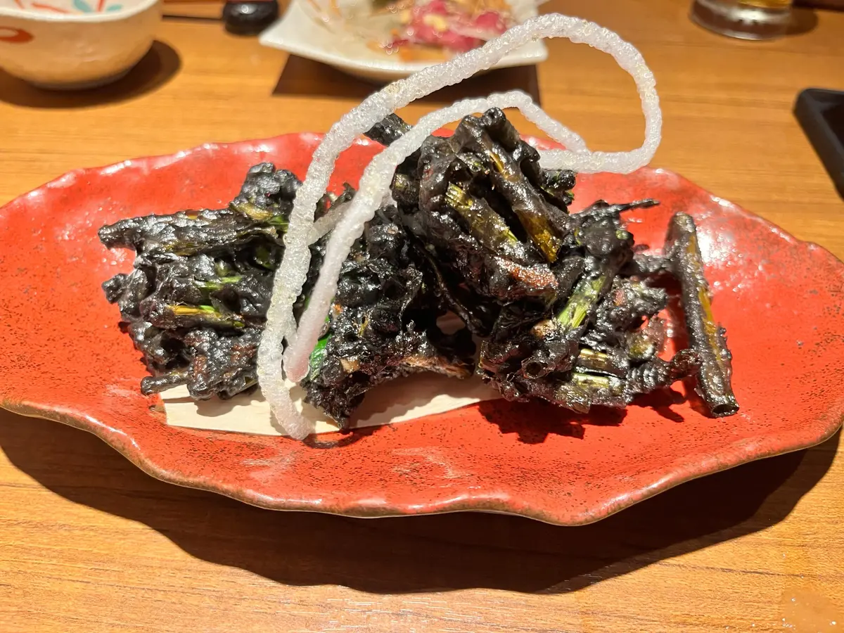 富山ブラックかき揚げ。イカスミの色を効かせる黒作りに衣をした、青ネギのかき揚げ。最高（涙）