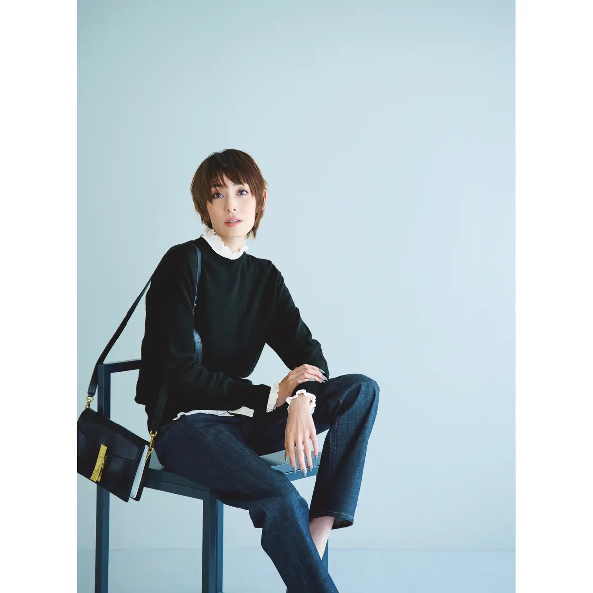 白フリルネックシャツと黒ニットの重ね着にデニムパンツを合わせたコーデ　モデル・LIZA