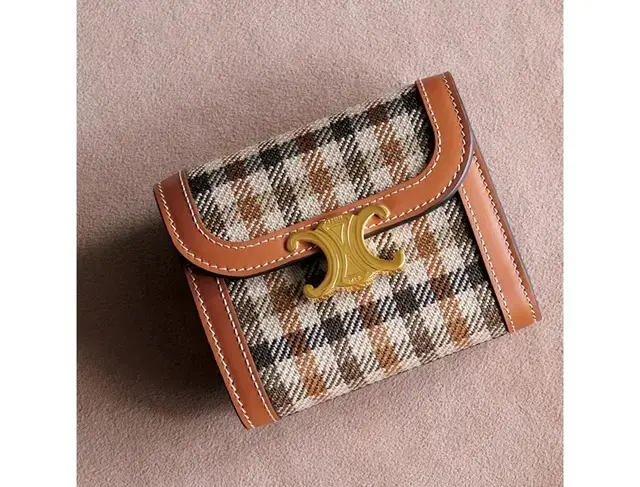 アイコニックなトリオンフのゴールドクロージャーがトラッドなタータンチェックと好相性。ブラウンのトリミングで上質なクラシカルさもまとって。