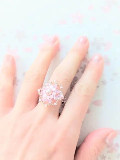 ピンク色のネイルにビーズの指輪を合わせた手元のおしゃれ