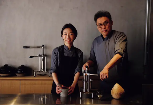 穂積依里シェフ（左）と、タイ時代に出会ったパートナーの石山公一さん。手前はオールドココナッツを搾るためのマシン。コースの口直しに