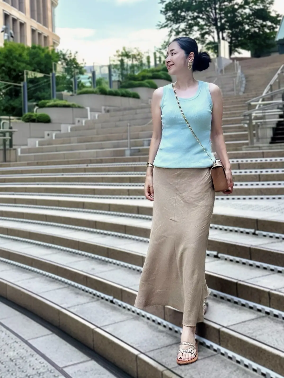 エクラプレミアムのキャメル「リネンフレアスカート」、ミントグリーンのノースリーブニット、キャメルショルダーバッグ、ゴールドのフラットサンダル