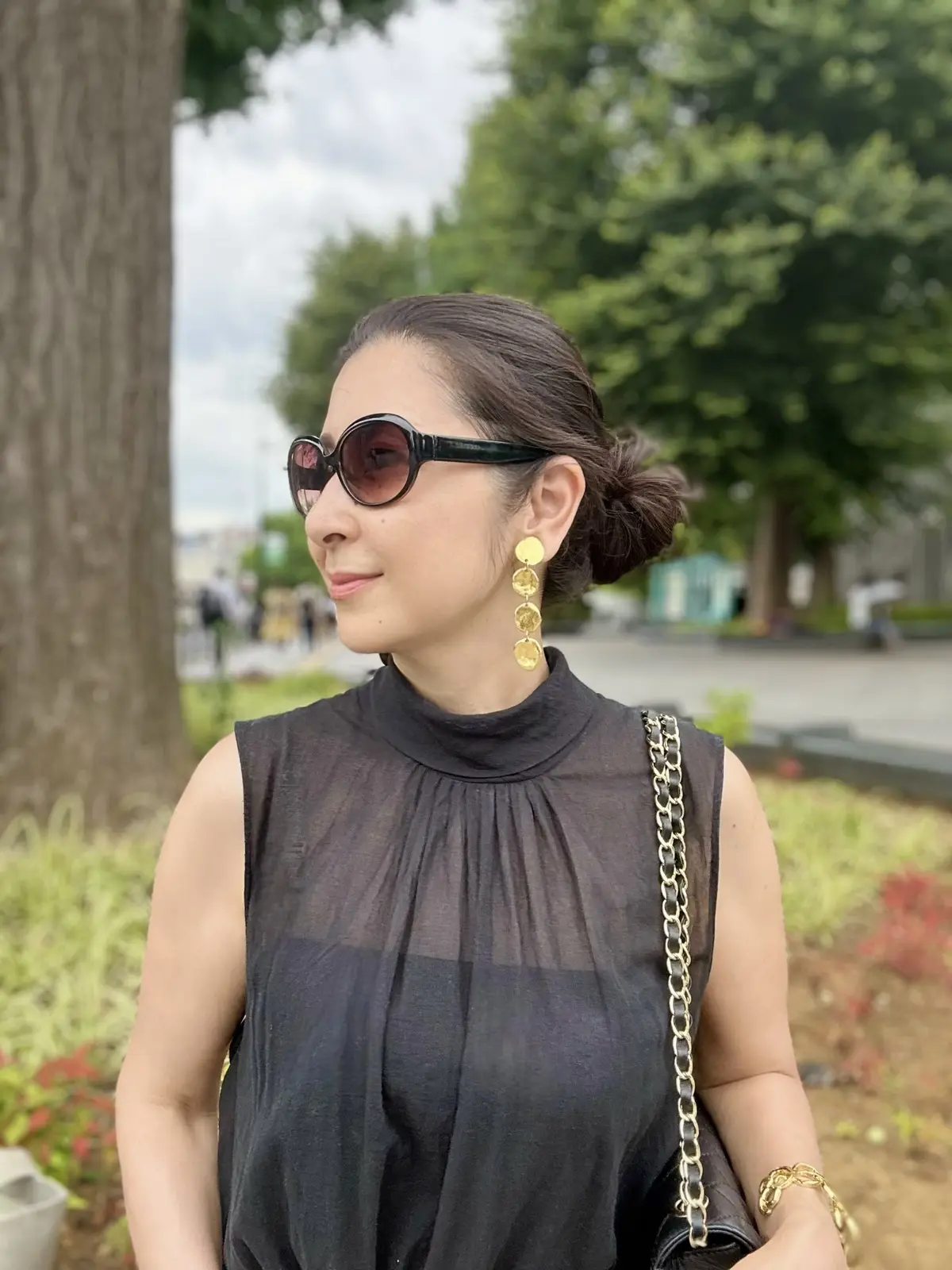 黒のノースリーブブラウス、ゴールドのイヤリング