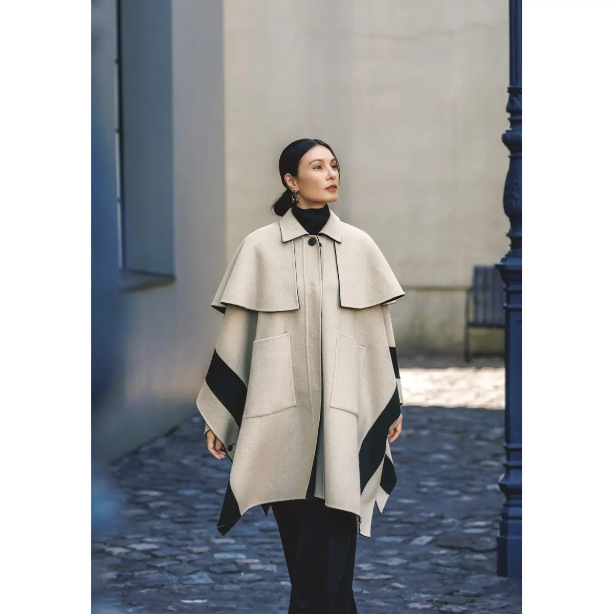 ベージュ×黒のケープ風コートに、黒タートルニットと黒パンツをあわせたコーディネート　モデル・田沢美亜