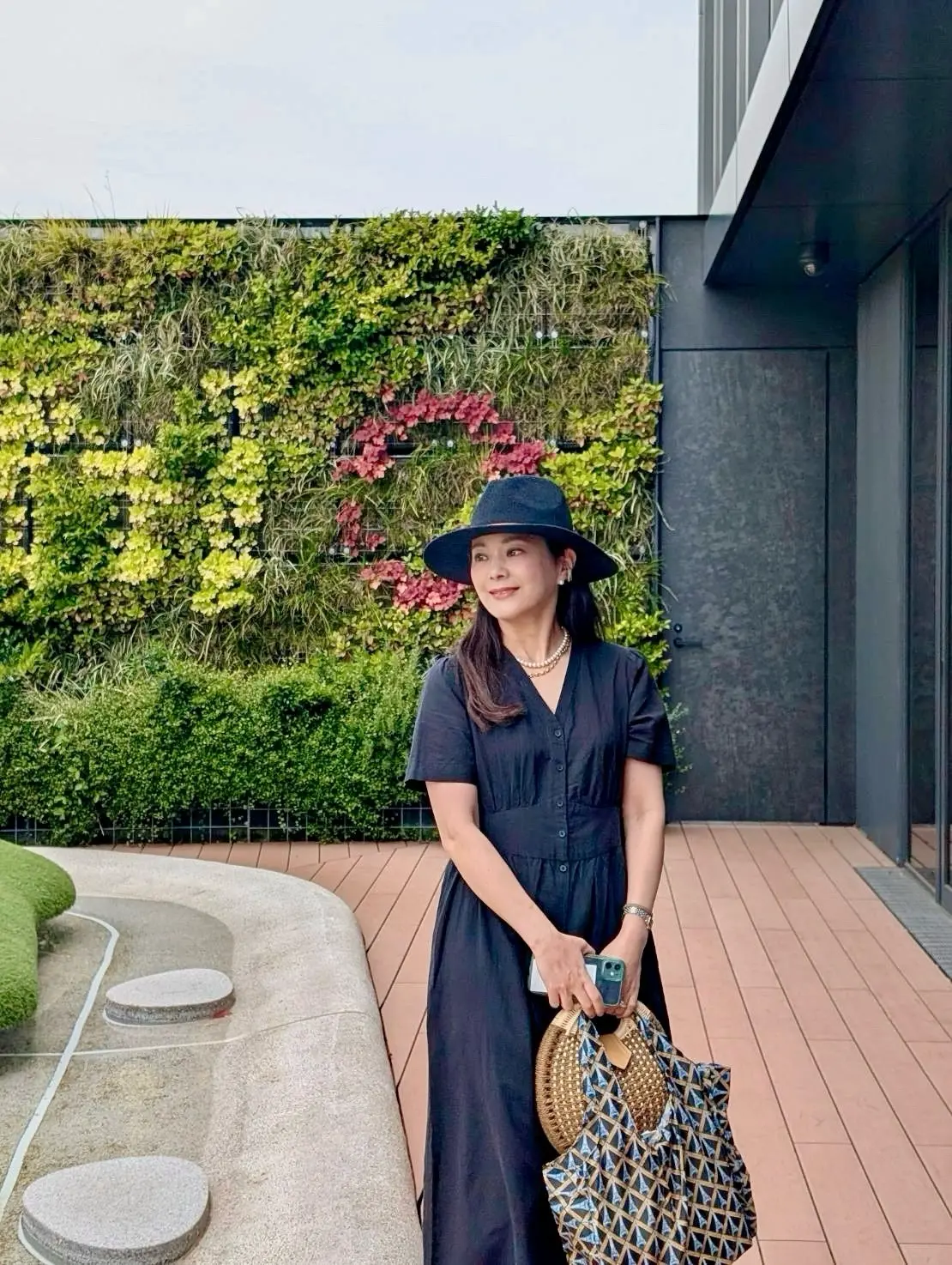 屋上テラスで風に揺れるグリーンを背景にユニクロのリネンワンピースとハット姿の爽やかなコーデ