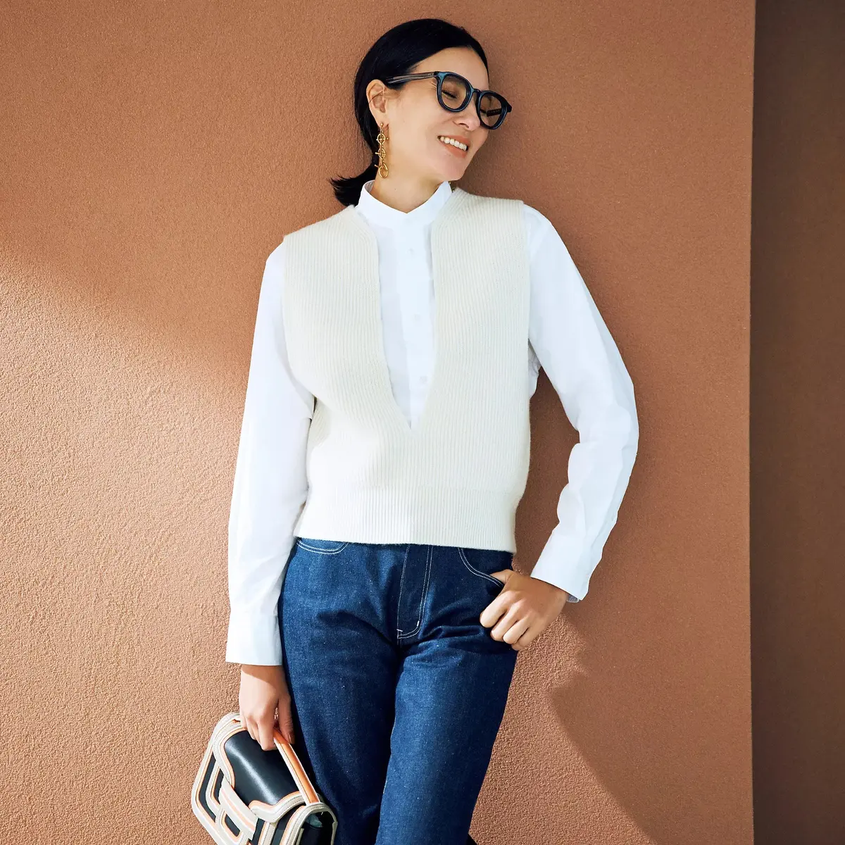 胸元の深いスリットデザインがニットベスト×シャツの装いにスタイリッシュな印象