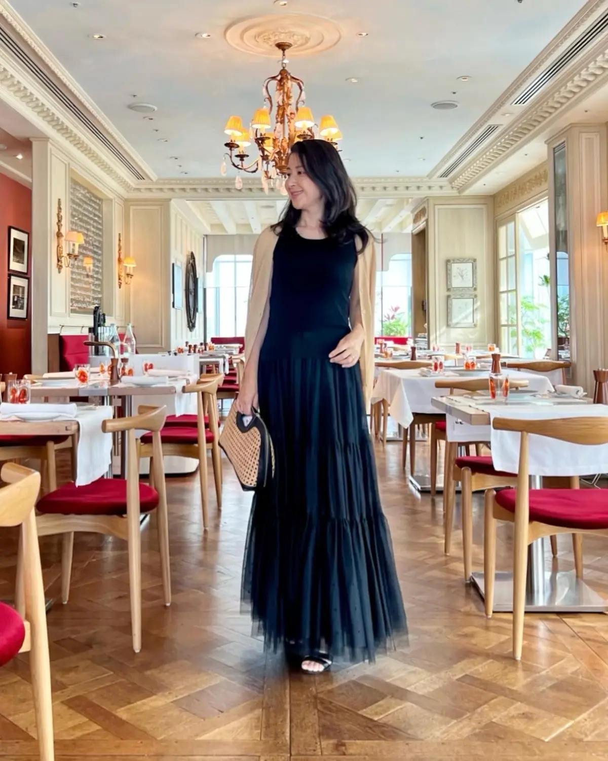 黒のノースリーブニット、黒のロングチュールスカート、黒のサンダル、黒レザーとカゴ素材んおハンドバッグ、イエローのカーディガン