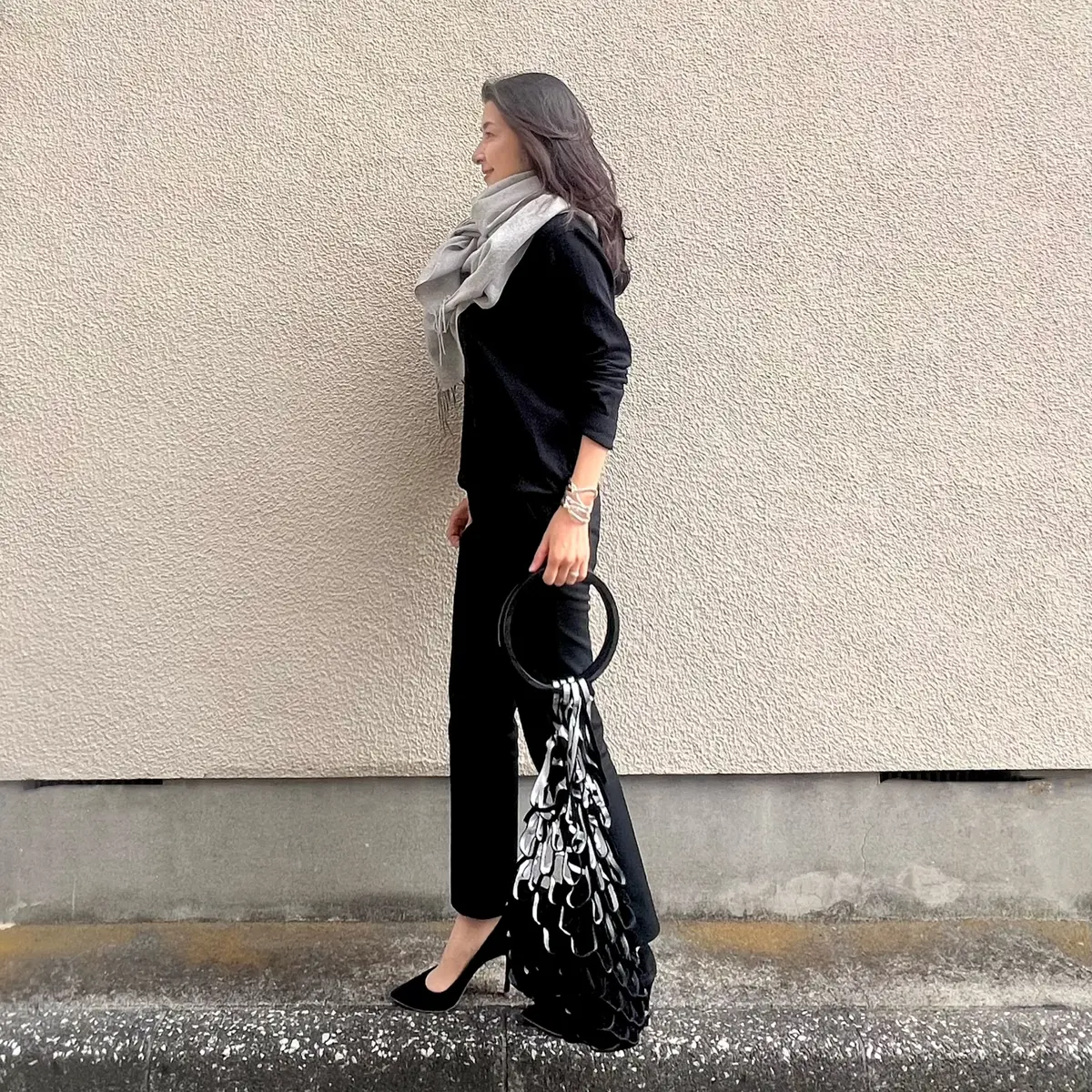 ユニクロ黒ニット、ユニクロ黒パンツ、黒パンプス、シルバーと黒のネットバッグ、ライトグレーの大判ストール