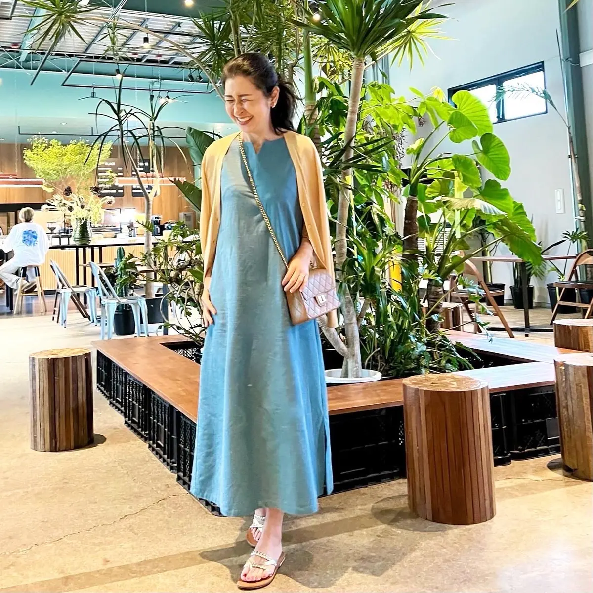 ブルー系ワンピース、キャメルのチェーンバッグ、ゴールドのフラットサンダル、イエローのカーディガン