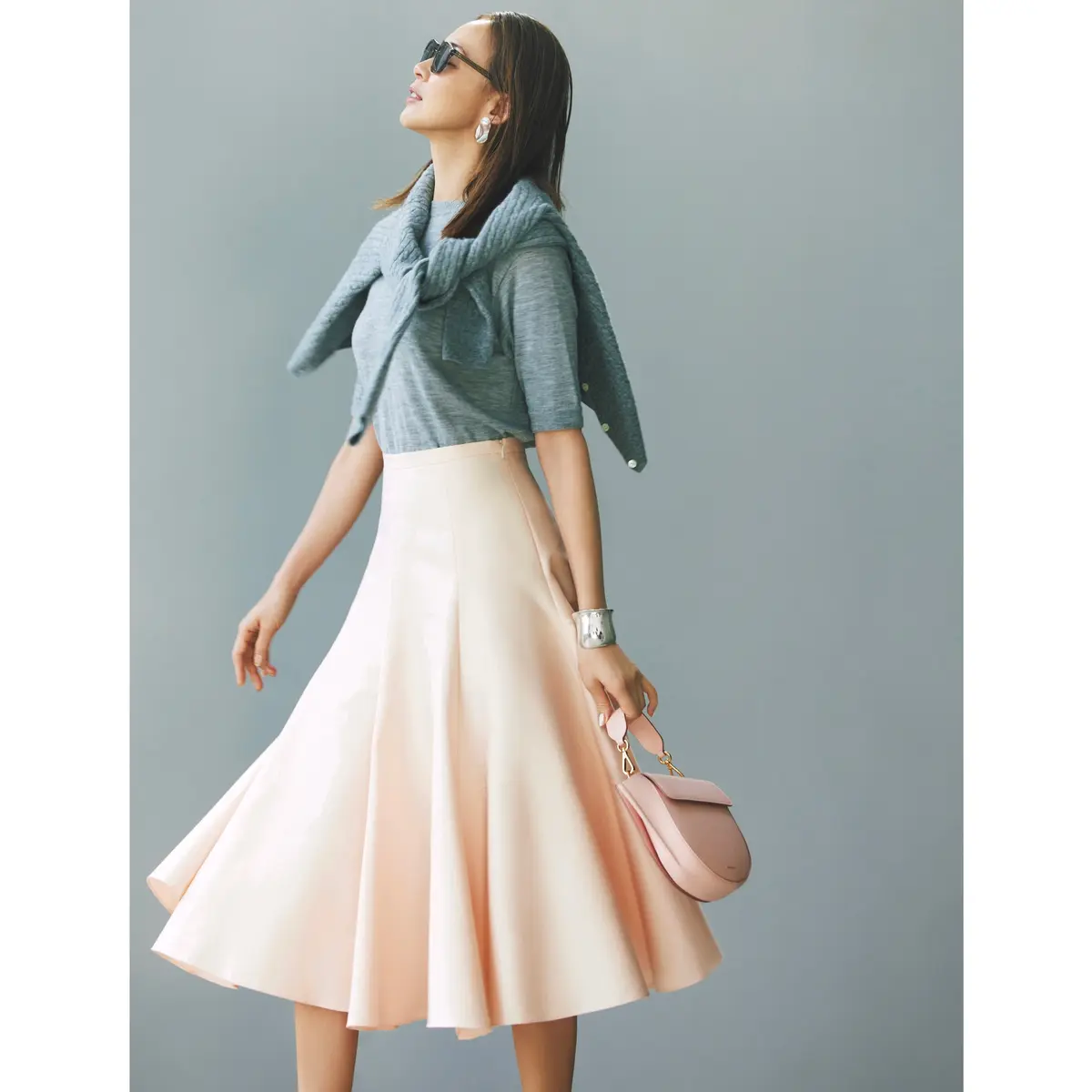 グレー半袖ニットにグレーカーデを肩がけして、ペールピンクのフレアスカートを合わせたコーディネート　モデル・SHIHO