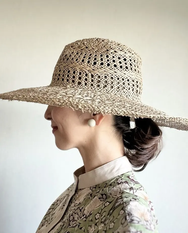 ハットの軽やかな透け感とリンクする、ラフなまとめ髪