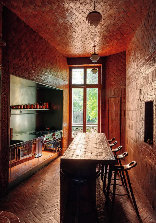 ラムダンは、キッチンのデザインでは箱をイメージし、床から壁、天井までを特製のテラコッタで敷きつめた。ただしタイルはすべて同じではなく、花のモチーフが描かれていたり、ややいびつだったり。左側の流しやコンロ、オーブンをまとめたユニットのステンレスには壁が反射し、いっそうドラマティックに