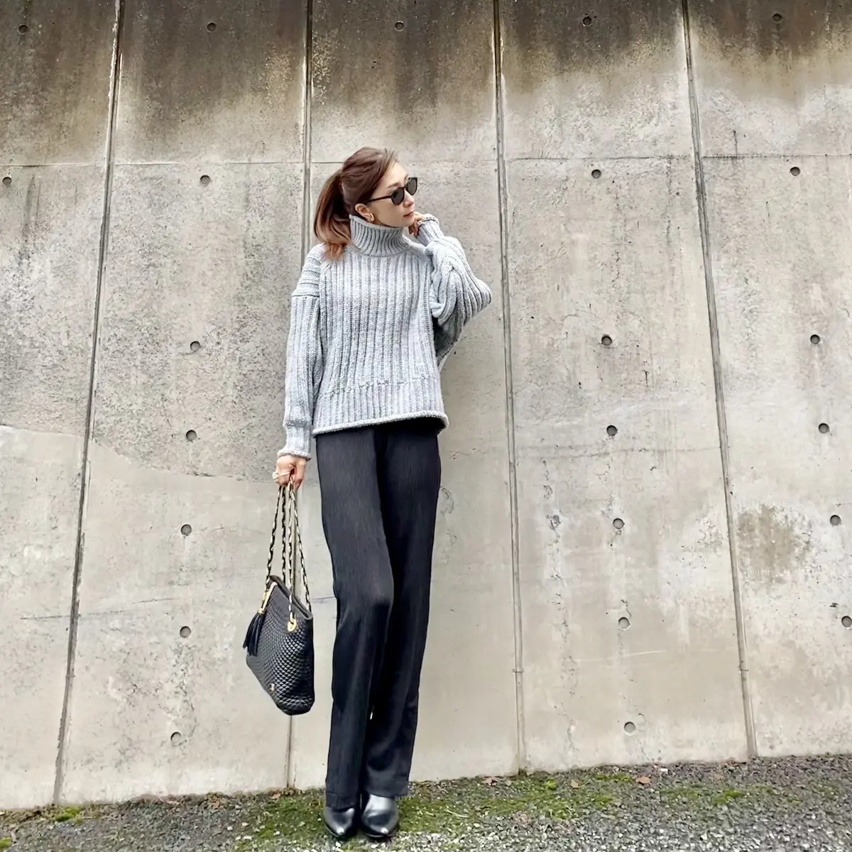 ライトグレーのチャンキーニットに黒パンツにショートブーツ