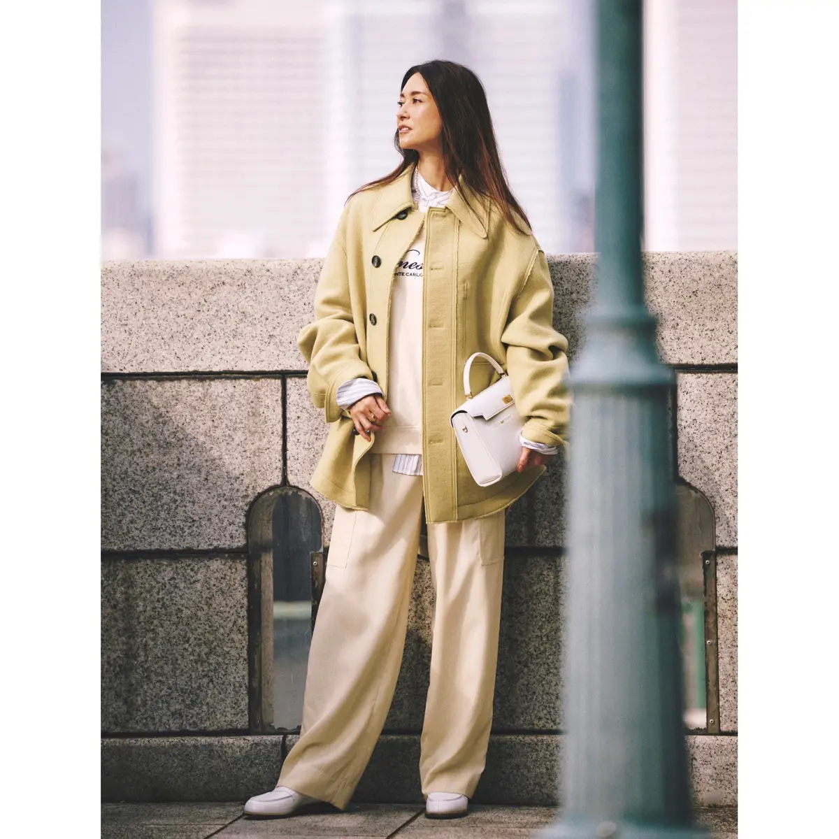 ストライプシャツとクリーム色のスエットを重ねた上にクリームイエローのCPOジャケットコートを羽織り、オフ白のゆるパンツを合わせたコーディネート　モデル・ブレンダ