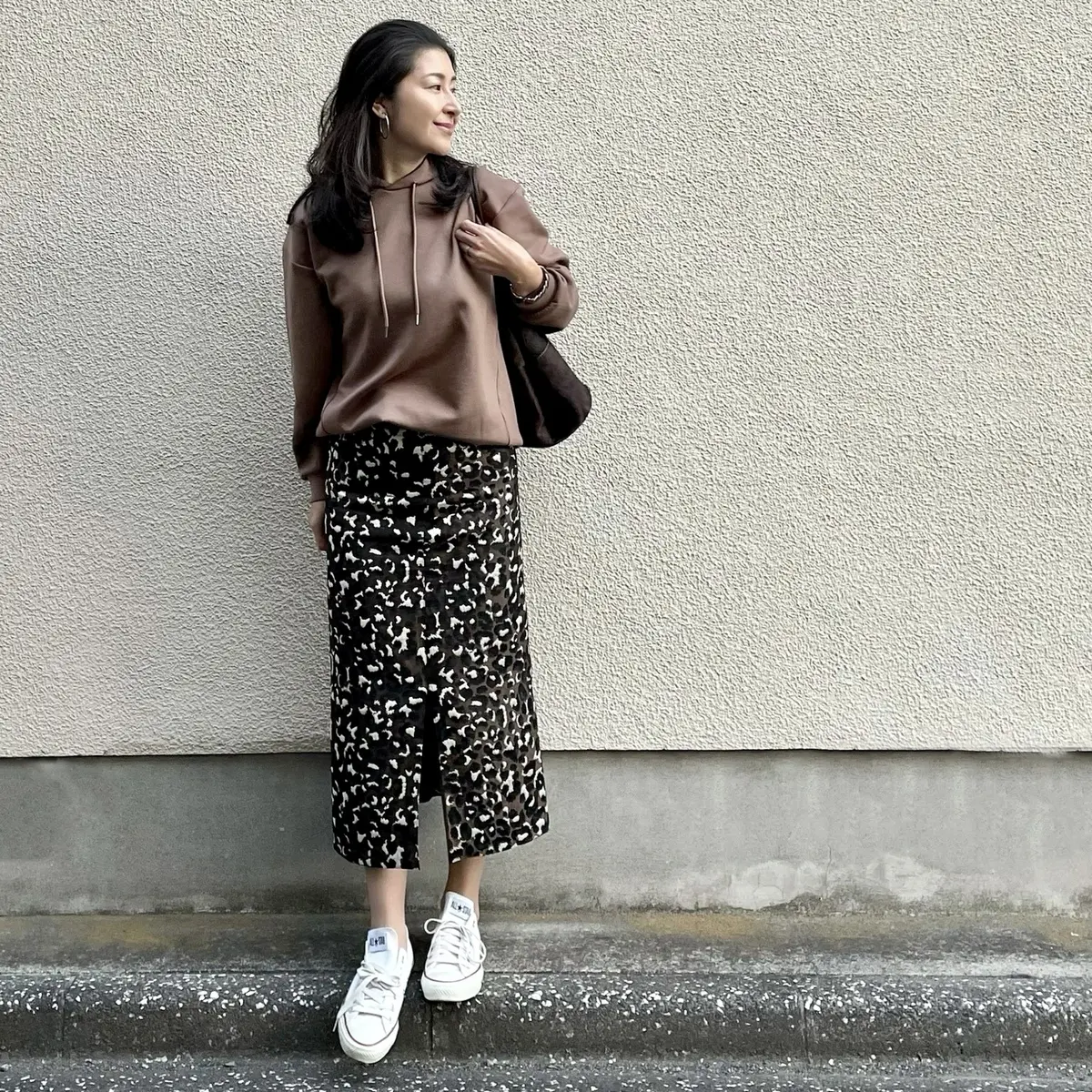 オレンジ系ブラウンのパーカー、レオパード柄タイトスカート、白のスニーカー、ブラウンのバッグ