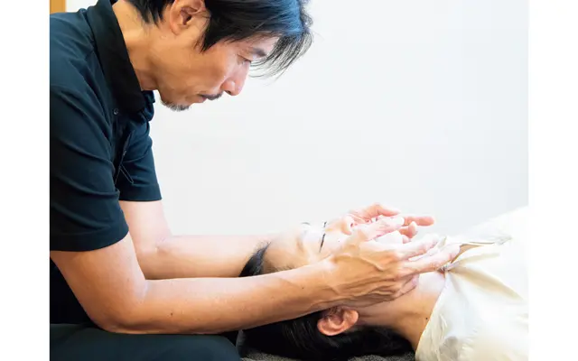 手のひらでフェイスラインを押しつつ、引き上げ、あごの関節の向きと、ずれた骨の位置を整える。