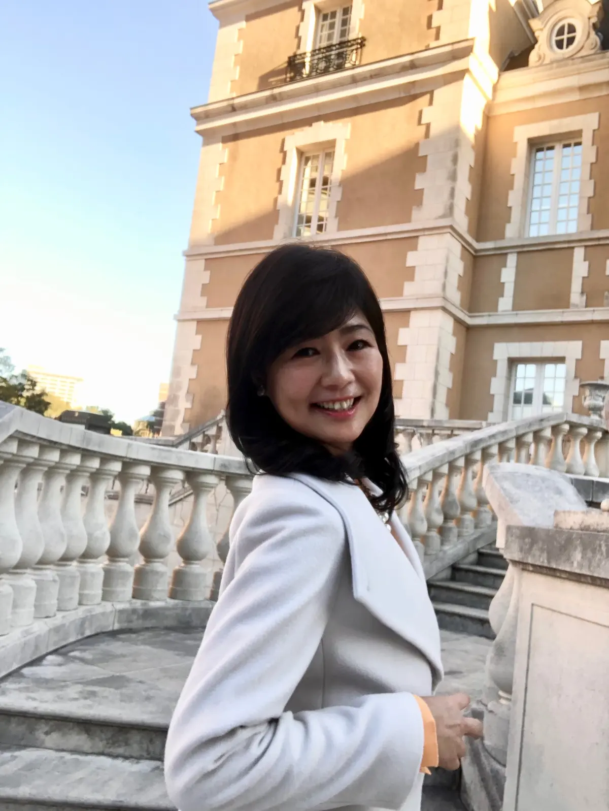 「ロペ」の白ロングコート。横から見てもスッキリスタイル。「リリーブラウン」のオレンジニット。