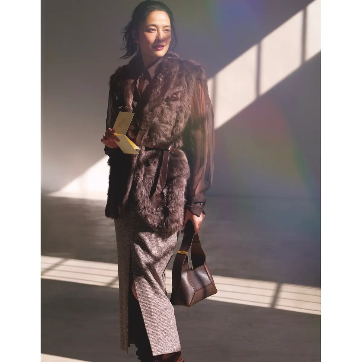 ブラウンのシアーブラウスにブラウンファーベストを重ね、ブラウンのタイトスカートを合わせたコーディネート　モデル・熊沢千絵