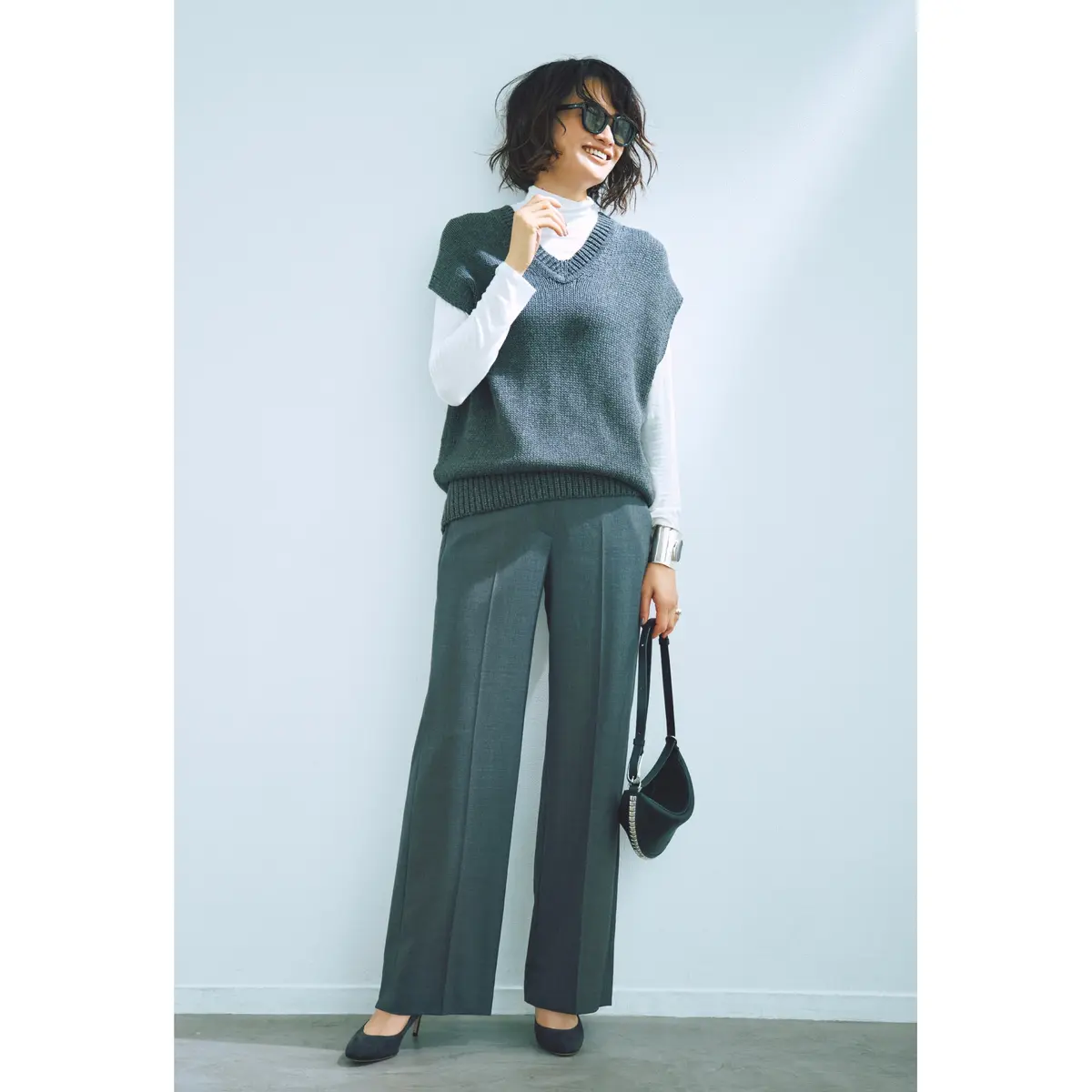 白ハイネックトップスにグレーベストを重ね、グレーセンタープレスパンツを合わせたコーデ　モデル・渡辺佳子