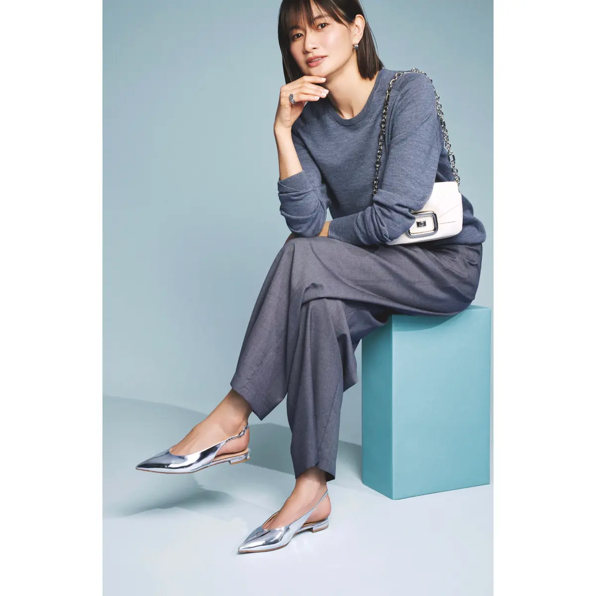 グレーニットとグレーパンツのコーディネートにシルバーミュールを合わせたスタイリング　モデル・渡辺佳子