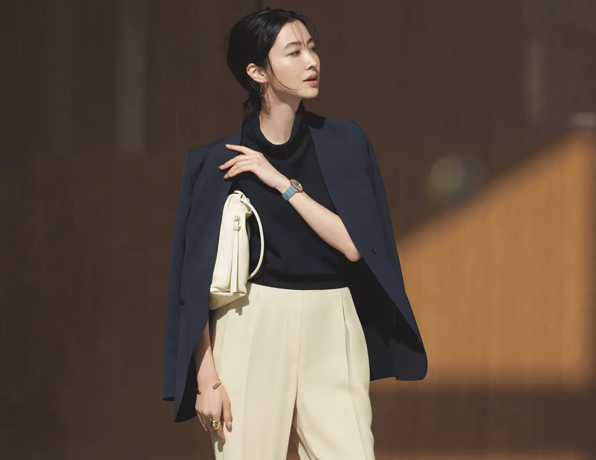 ネイビーノーカラージャケットに黒スタンドカラートップスとベージュパンツを合わせたコーデ　モデル・絵美里