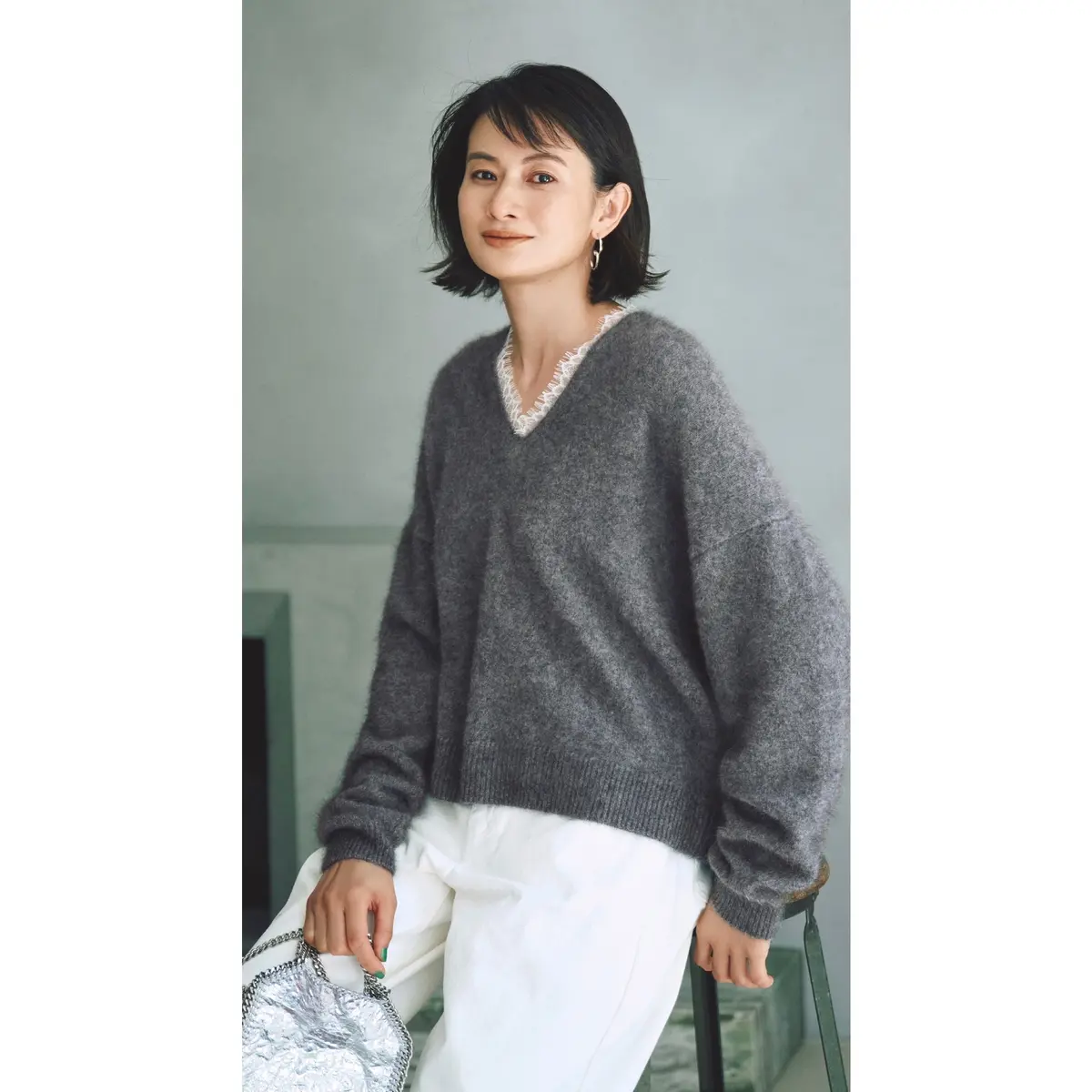 白レースが首元についたグレーVネックニットに白パンツを合わせたコーディネート　モデル・渡辺佳子