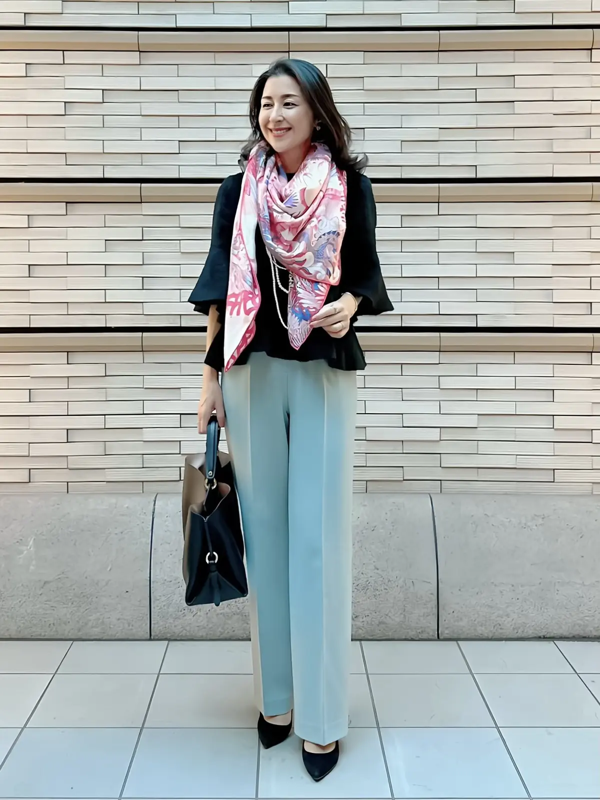 コーデ写真　ブルーパンツ、黒のニットブラウス、ピンクの柄ストール、黒パンプス、黒バッグ