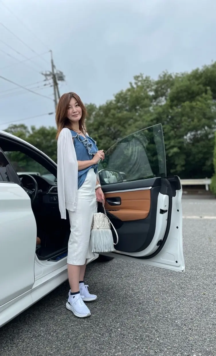 白い車の前に立つ女性