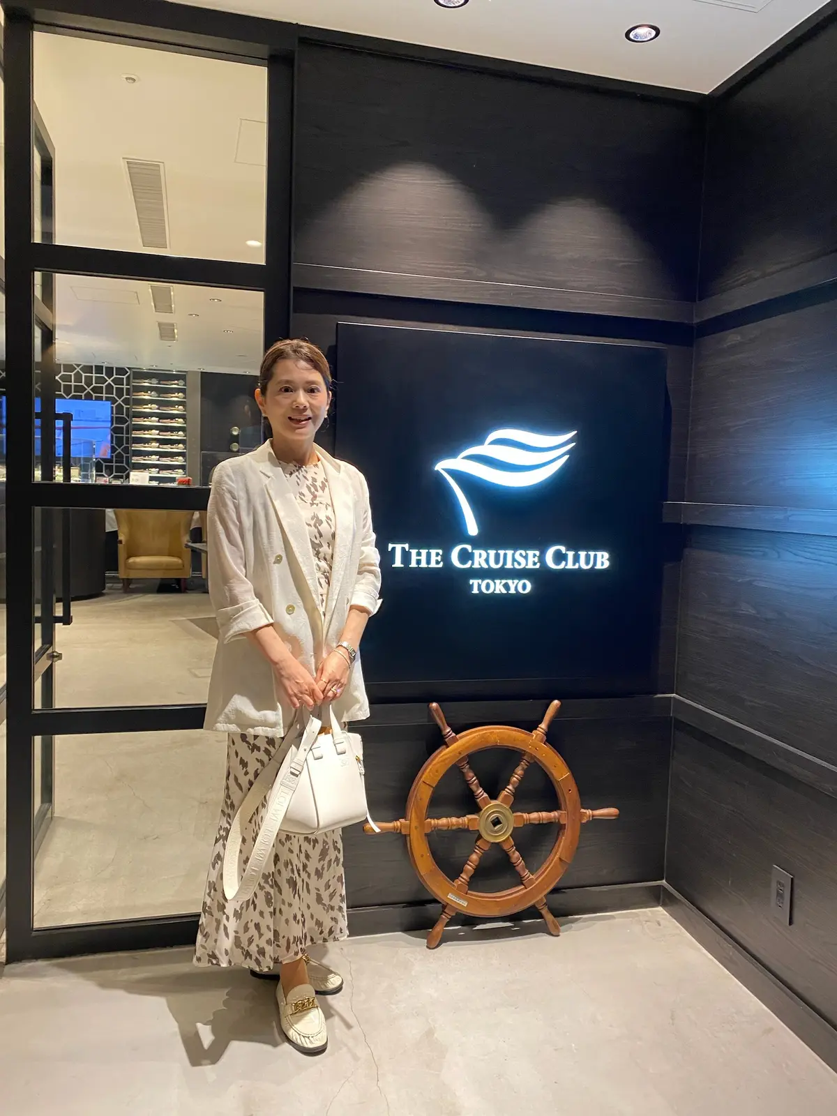 シアージャケットに柄シフォンワンピース、白のローファーを合わせたホワイトトーンのクルーズコーデ。品のある大人のスタイル