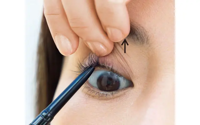 ペンシルはまつ毛の下側から当てる。まつ毛の生えぎわがよく見えるように、片方の手でまぶたを引き上げる。