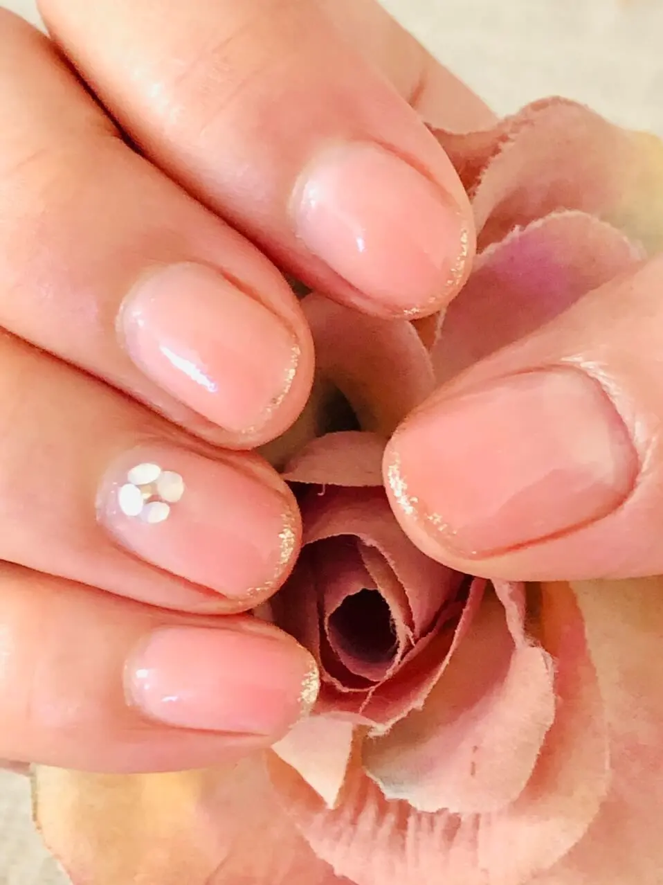 この日のジェルネイル。クリアピンクのネイルにストーンでお花を。爪の先端にはラメラインを。