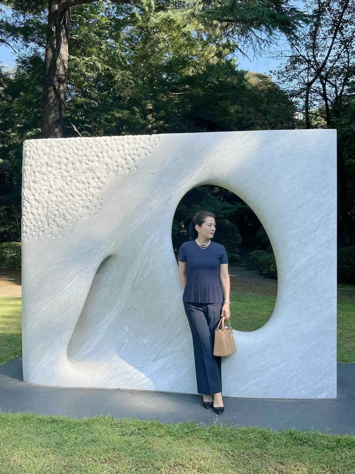 東京都庭園美術館の正門前で撮影したネイビーの秋コーデ。ユニクロのスマートフレアパンツにフェラガモのトップスを合わせたきれいめスタイル。