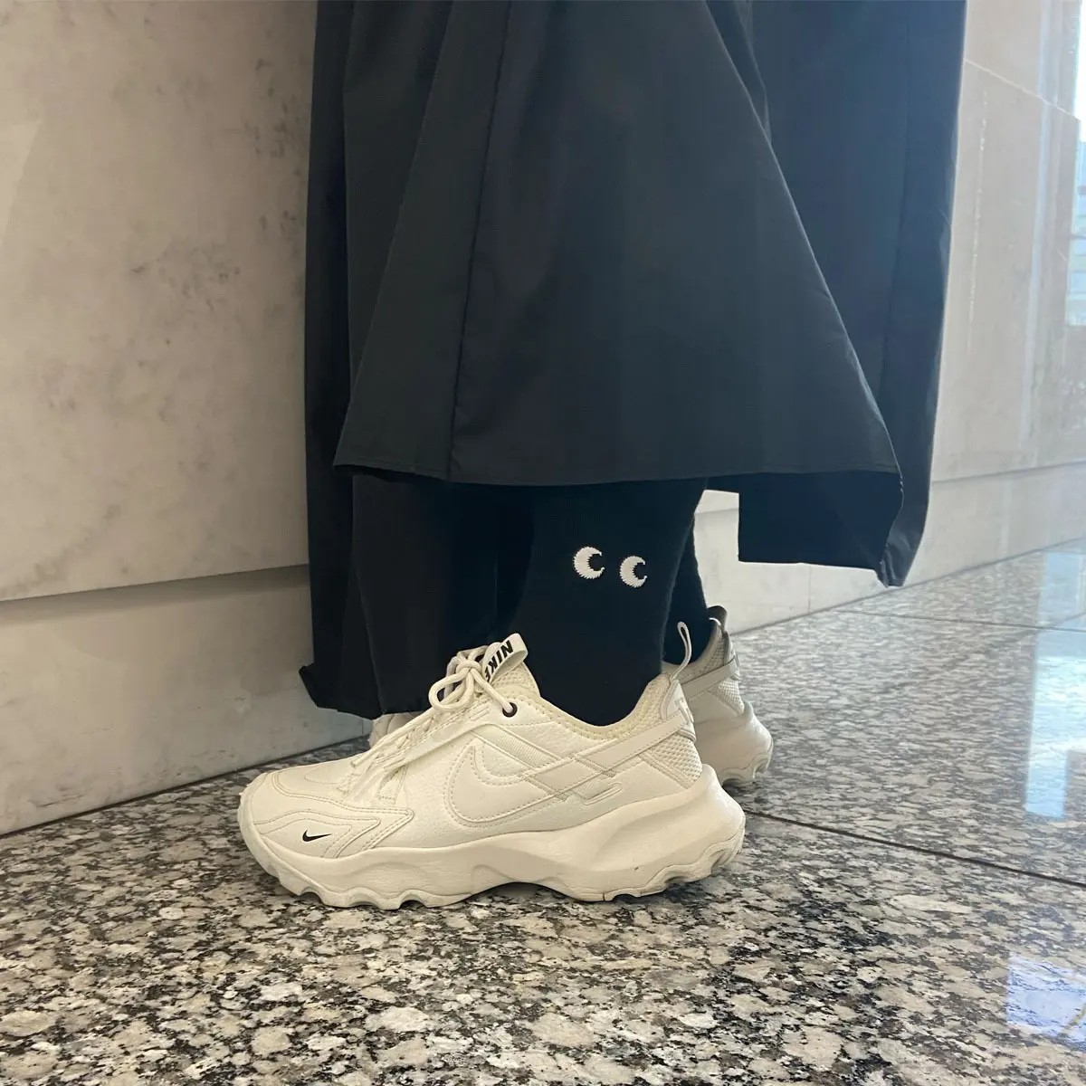 たっぷりとボリュームのある黒いロングスカートの足元に白スニーカーを効かせたS林。