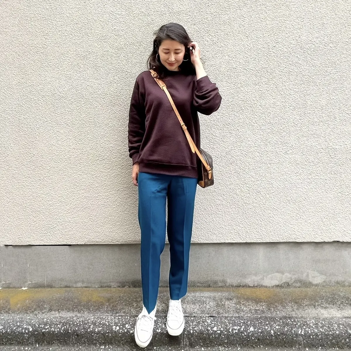 GUスウェットシャツ、ブラウン、ブルーのパンツ、白のスニーカー、ブラウンのポシェット