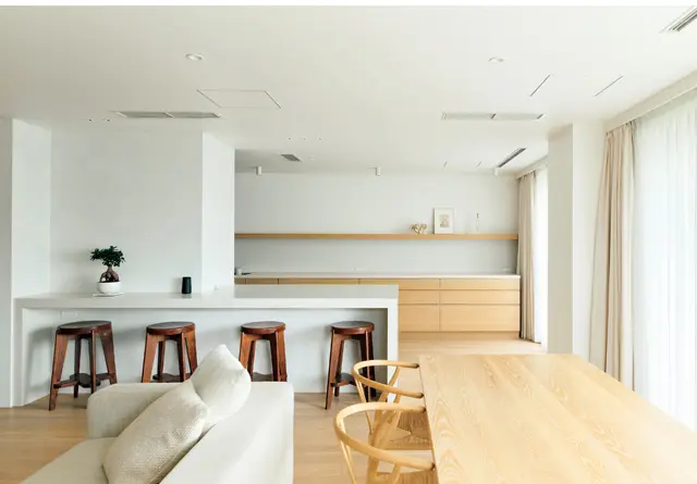 リビングダイニング側から見るキッチンはこんなにもすっきり、整然としている。「収納場所をきちんと造ってくださったので、常にこの状態をキープできています」とYさん。4脚並べたハイスツールは、ピエール・ジャンヌレがデザインしたヴィンテージ。 AD COREのダイニングテーブルにYチェアを合わせた　