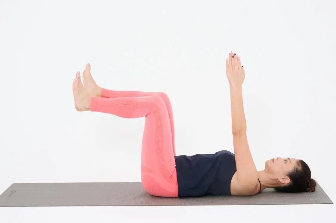 OurAge×Webエクラ あお向けになり、両脚を上げて膝と股関節を90度に曲げ、両腕は真っすぐ上に伸ばし、お腹をぺたんこにします。