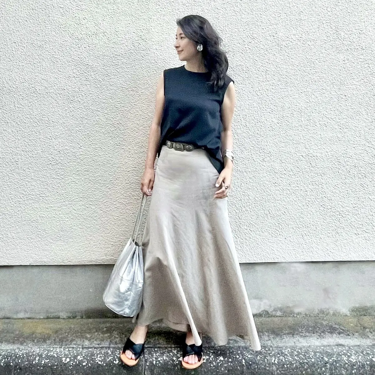 黒のノースリーブブラウス、ベージュのマーメイドマキシスカート、黒のフラットサンダル、シルバーのバッグ