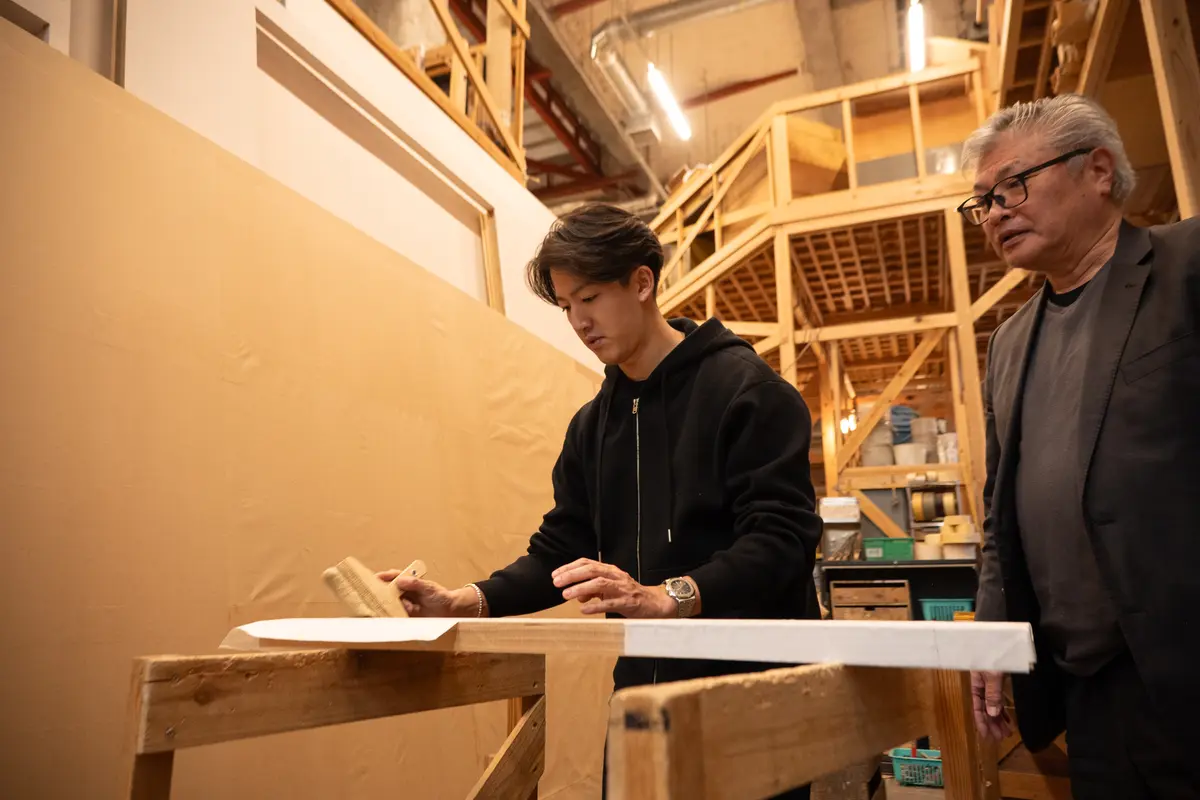 糊を塗った紙を刷毛ではっていく作業を体験。隣は幼少時代頃から知っている窪田丈和さん。